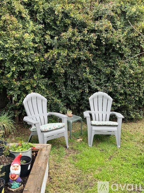 Two chairs and a table are in a garden.