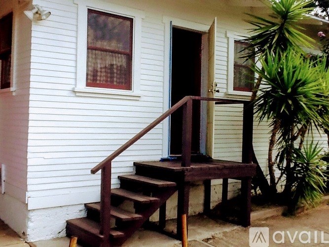 A white house with a black door and a wooden staircase.