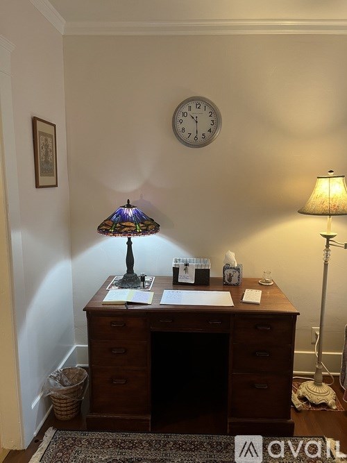A desk with a lamp and a clock on the wall.