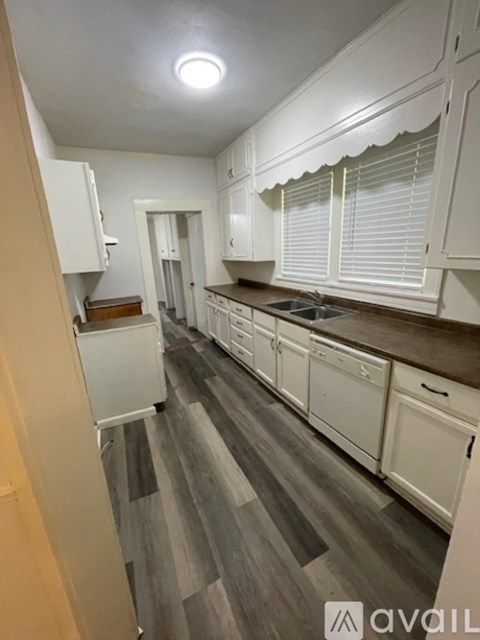 A kitchen with white cabinets and a wooden floor.