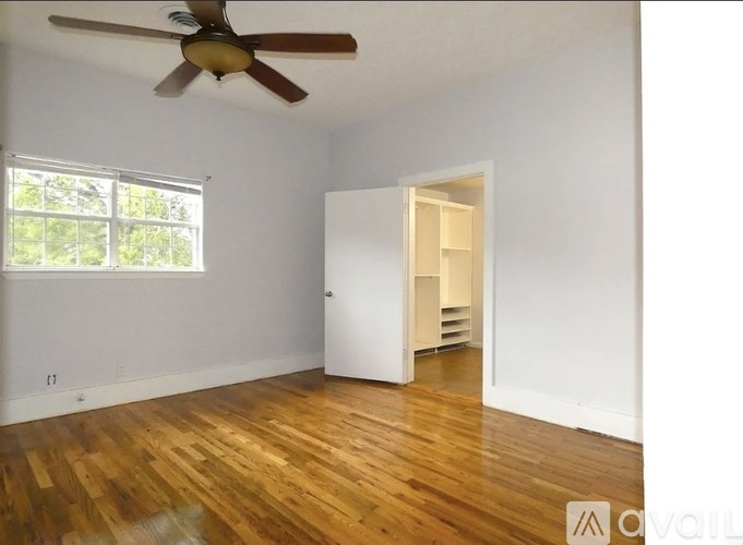 A room with a ceiling fan and wooden floors.