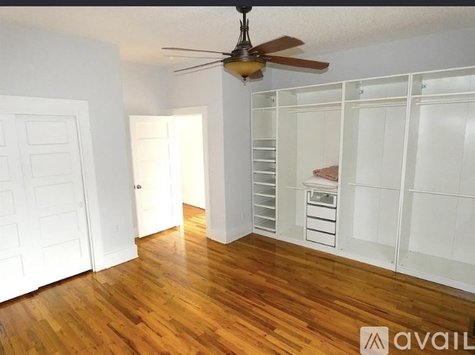 A room with a ceiling fan and wooden floors.