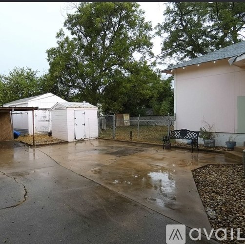 A white tent is set up in a driveway next to a pink building.