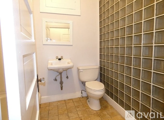 A bathroom with a toilet, sink, and tiled wall.