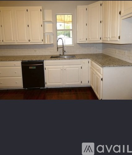 A kitchen with white cabinets and a black trash can.
