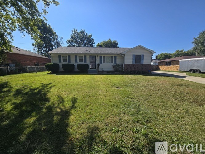 A house with a white fence and a green lawn in front.