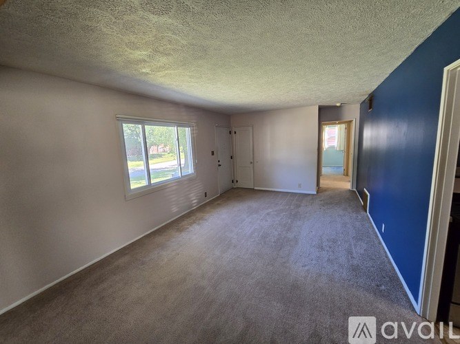 A room with a carpeted floor and a window with blinds.
