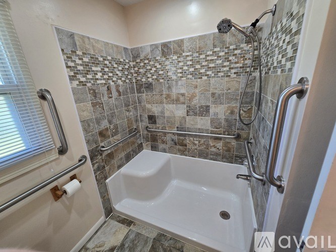 A shower area with a white tub and a tile wall.