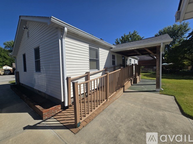A white house with a brown railing and a covered patio.