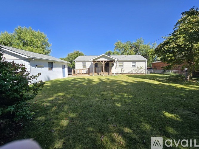 A backyard with a white house and a green lawn.