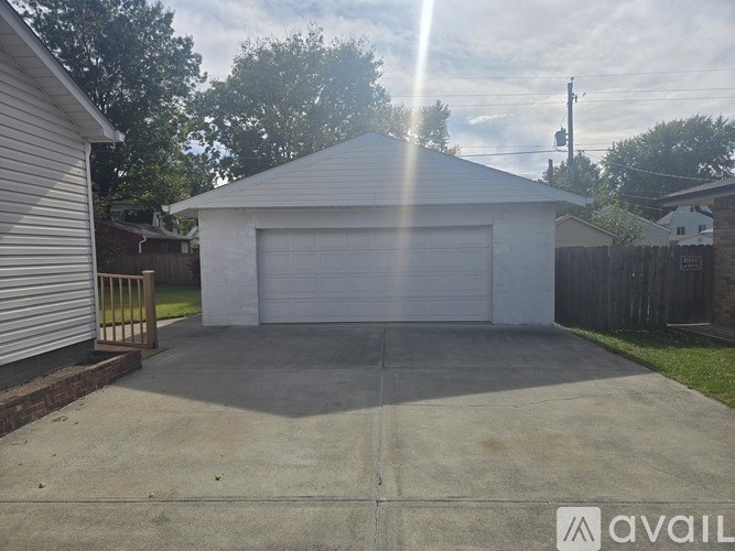 A white garage door is open in a driveway.