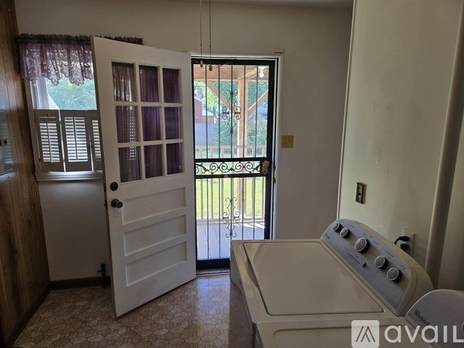 A room with a white door, a window with a view of a balcony, and a white oven.
