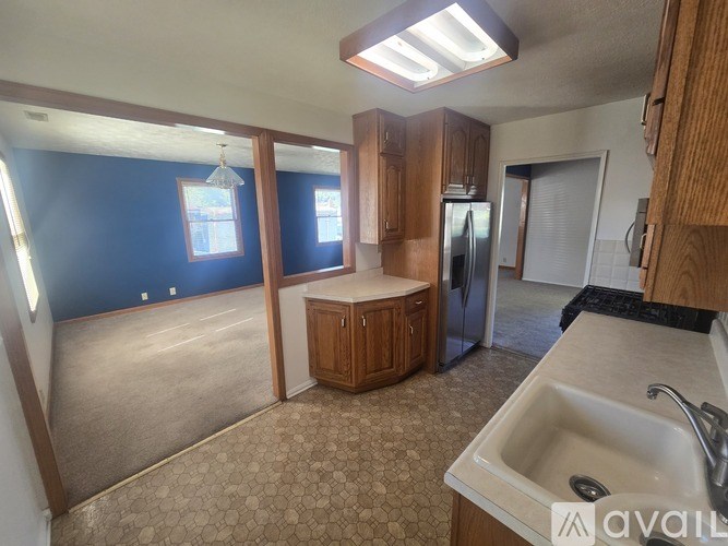 A kitchen with a sink, refrigerator, and cabinets.