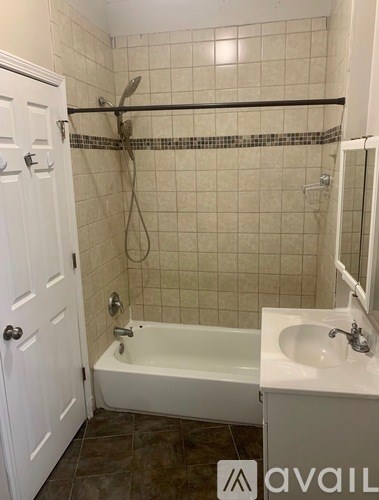 A bathroom with a white tub, sink, and tiled walls.