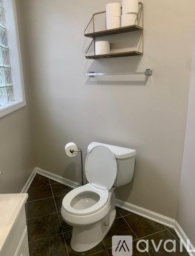 A white toilet in a bathroom with a shelf above it.