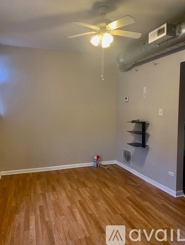 A room with a ceiling fan and a wooden floor.