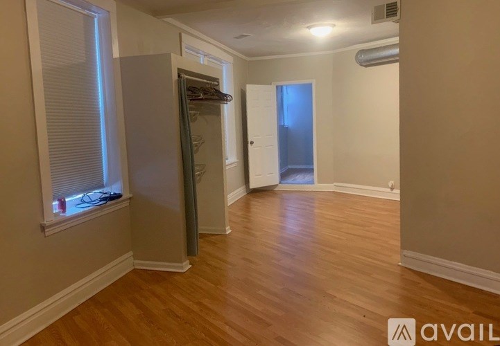 A room with wooden flooring and a refrigerator.