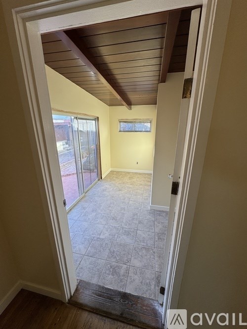 A room with a tiled floor and a slanted ceiling with a doorway leading to a balcony.