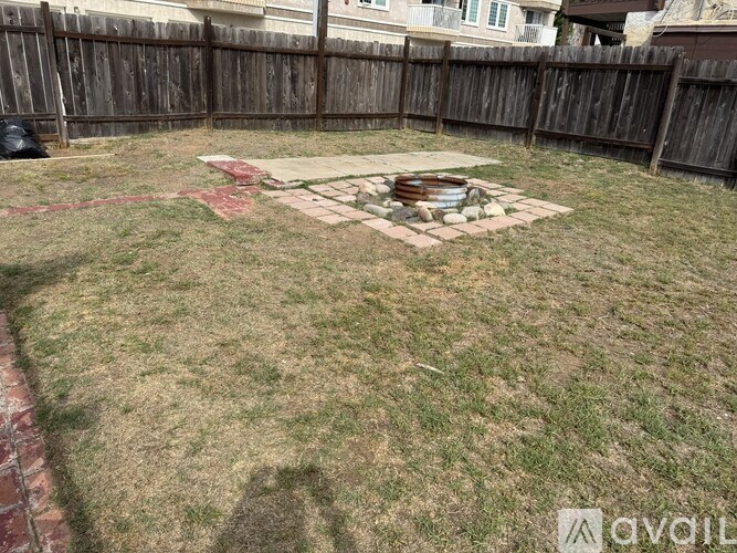 A backyard with a fire pit and a wooden fence.