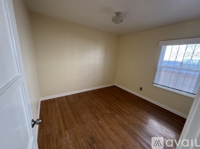 A room with wooden flooring and a window with blinds.
