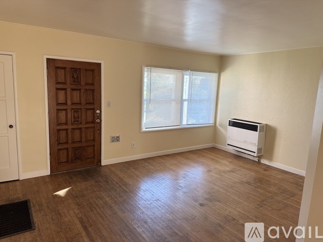 A room with a wooden door and a window with blinds.