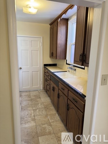 A kitchen with wooden cabinets and a tiled floor.