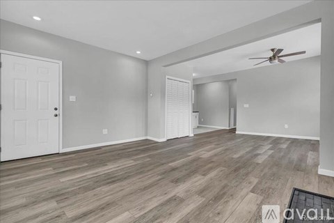 A spacious room with wooden flooring and a ceiling fan.