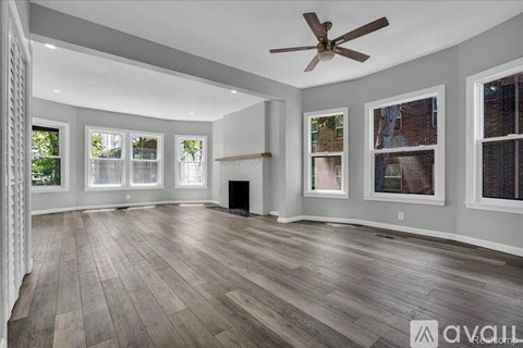 A spacious room with wooden flooring and a ceiling fan.