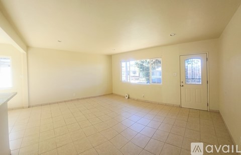A spacious room with tiled flooring and a door with a window.