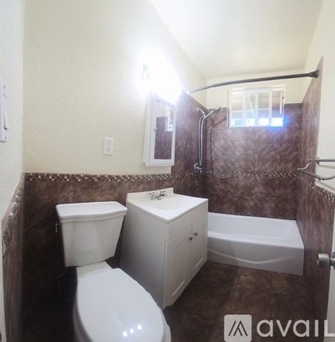 A bathroom with brown tiles and a white toilet.