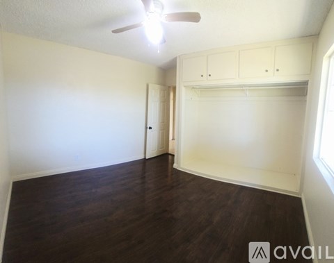 A room with a ceiling fan and wooden flooring.