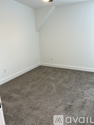 A carpeted room with white walls and a small window.