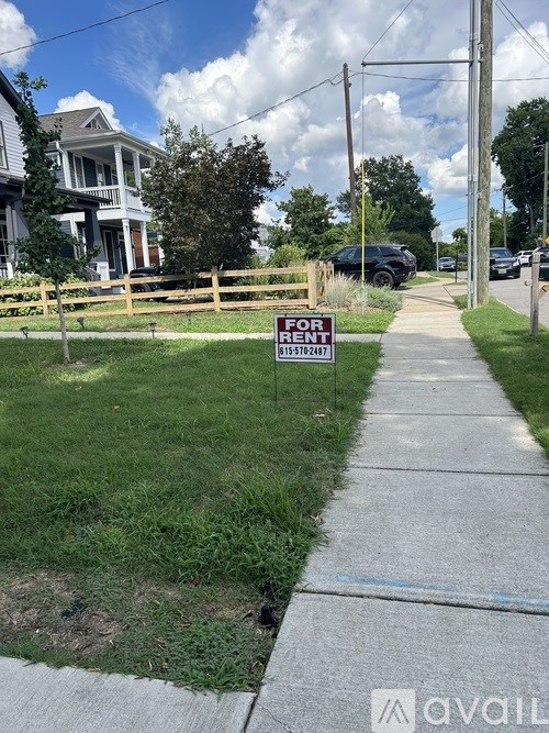 A "FOR RENT" sign is on a lawn in front of a house.