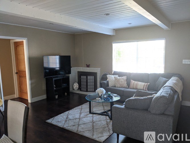 A living room with a grey couch, a black entertainment center, and a glass coffee table.