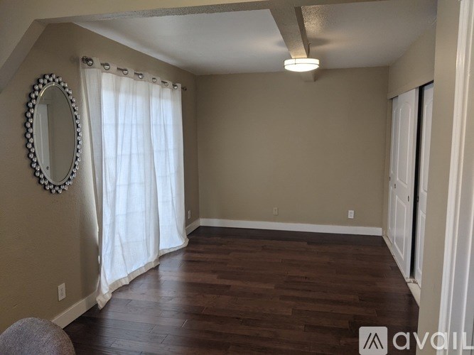 A room with a wooden floor and a white curtain.