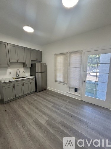 A kitchen with a refrigerator, cabinets, and a window.