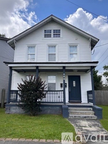 A two-story house with a blue door and white siding.