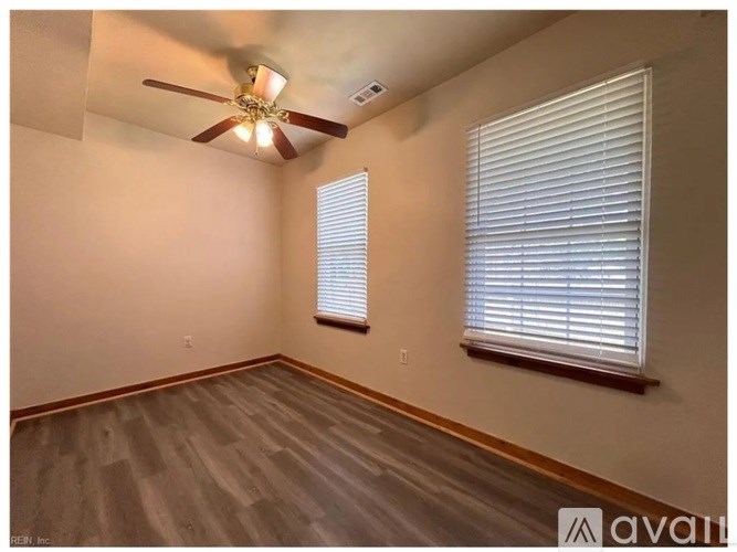 A room with a ceiling fan and a window with blinds.