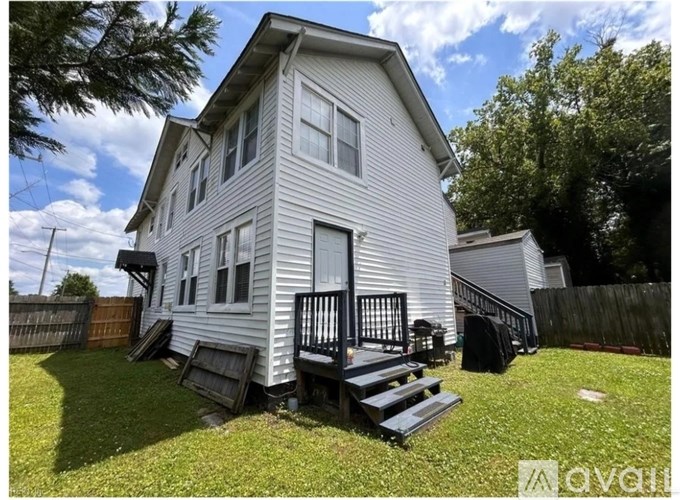 A two-story house with a deck and a fence.