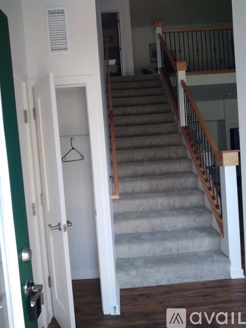 A hallway with a staircase and a door with a hanger on it.
