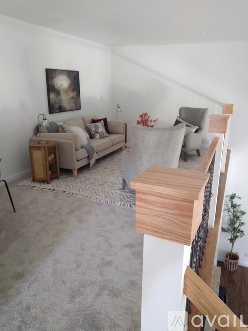 A living room with a couch, a chair, and a small table with a vase on it.