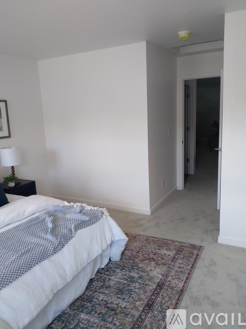 A bedroom with a bed, a lamp, and a rug.