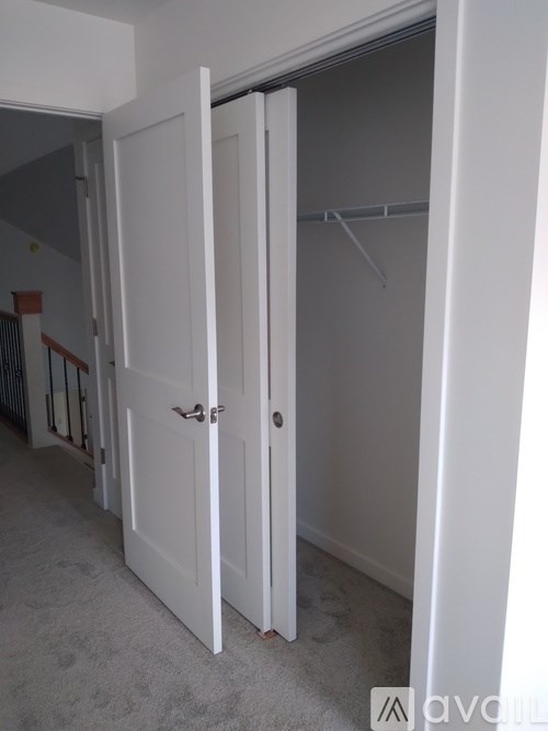 A white door is open to a room with a grey carpet.
