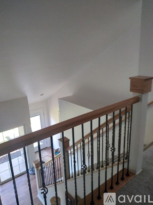 A staircase with a wooden handrail and black balusters.