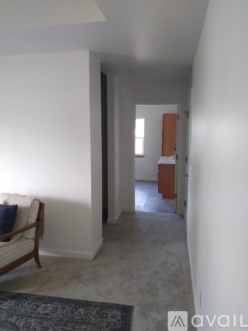 A room with a carpet and a chair with a blanket on it.