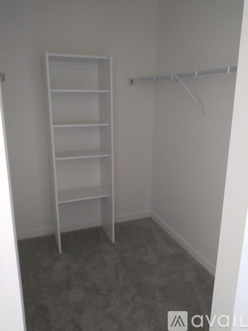 A white shelving unit in a room with grey carpeting.