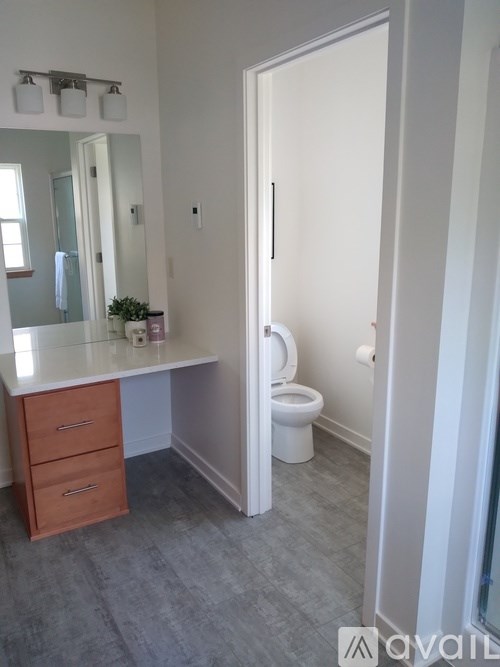 A bathroom with a toilet and a vanity with a mirror.
