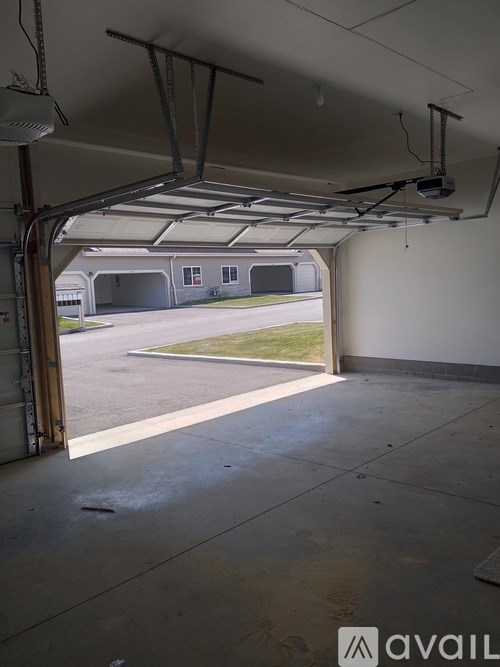 A large open garage door with a view of a road and a building in the distance.