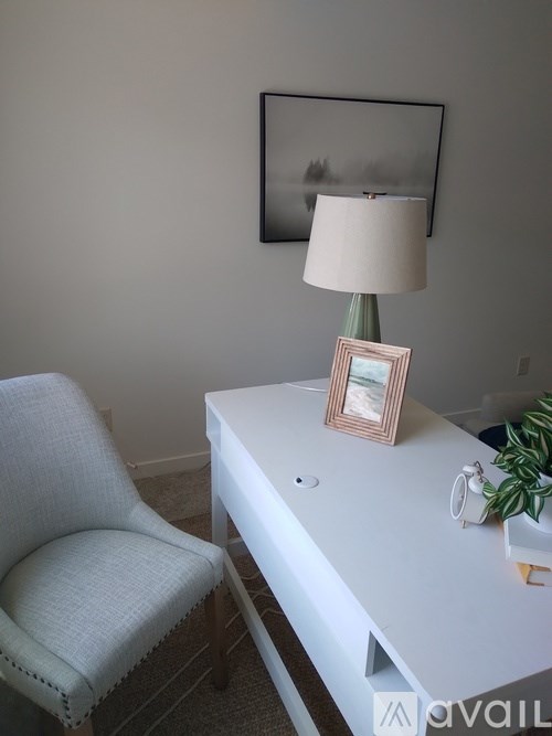A white desk with a lamp and a picture frame on it.