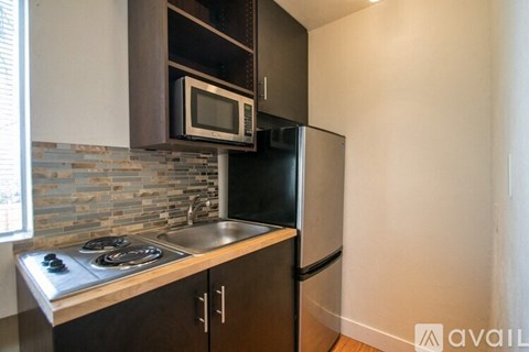 A kitchen with a black refrigerator and a stove top oven.